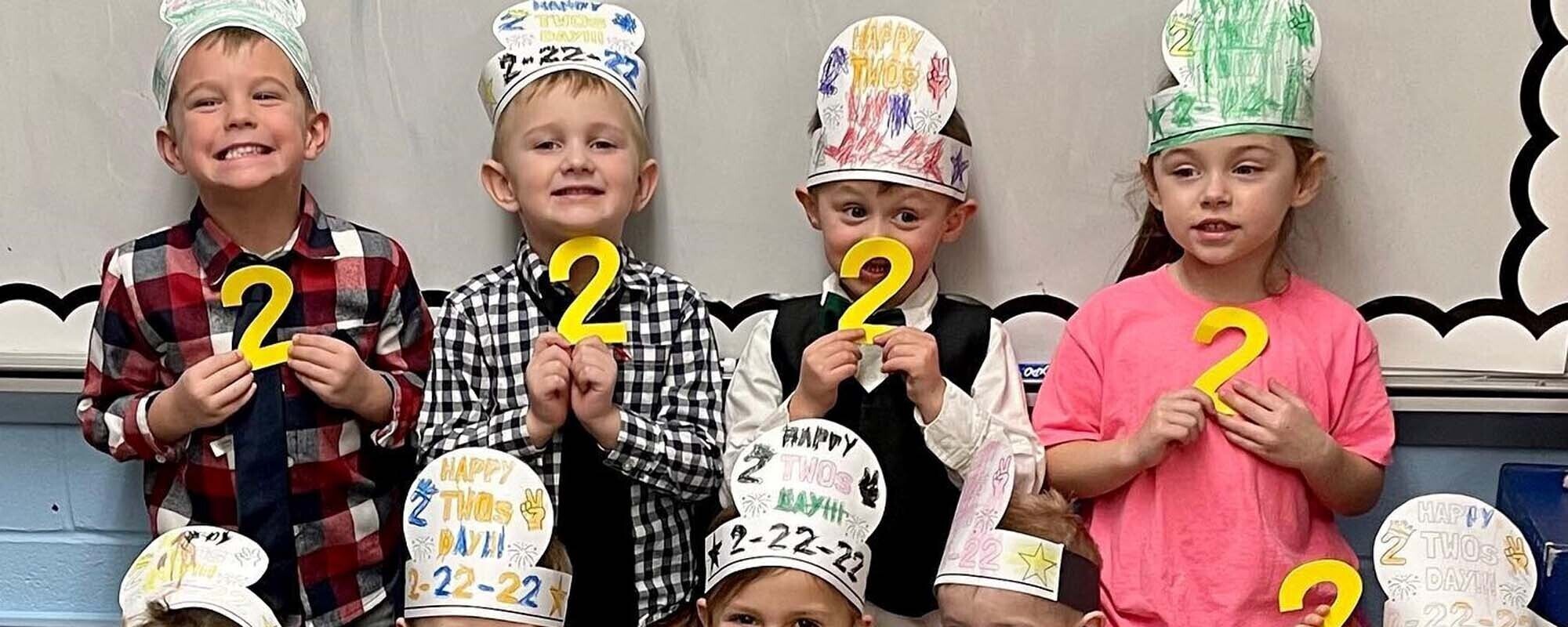 Elementary students holding the number 2